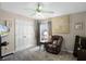 Cozy bedroom with comfortable reclining chair, decoratively painted ceiling fan, and natural lighting at 3033 Zaharias Dr, Orlando, FL 32837