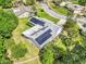 Bright aerial view of a home with solar panels surrounded by lush green landscaping and mature trees at 381 Red Mulberry Ct, Longwood, FL 32779