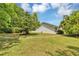 This home has a large, grassy backyard with trimmed bushes, lovely landscaping, and white siding at 381 Red Mulberry Ct, Longwood, FL 32779
