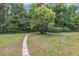 Landscaped backyard featuring lush grass, an abundance of trees, and a stone pathway at 381 Red Mulberry Ct, Longwood, FL 32779