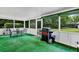 Enclosed back porch with green carpet, glass table with four chairs, and an outdoor grill at 381 Red Mulberry Ct, Longwood, FL 32779