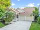 Charming home featuring a two-car garage, well-maintained lawn, and tropical landscaping for great curb appeal at 5044 Wise Bird Dr, Windermere, FL 34786