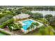 Aerial view of a luxurious community pool area featuring a large pool, clubhouse, palm trees, and lakeside location at 5044 Wise Bird Dr, Windermere, FL 34786