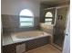 A bathroom featuring a bathtub, a shower, decorative tiles and an arched window at 5406 Crepe Myrtle Cir, Kissimmee, FL 34758