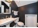 Striking powder room featuring dark walls, stylish fixtures, and a unique mirror creating a modern aesthetic at 5479 Baytowne Pl, Oviedo, FL 32765