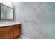 Powder room showcasing a wood vanity, marble countertop, decorative mirror, and a lovely textured blue wall at 6125 Foxfield Ct, Windermere, FL 34786