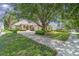 Paver driveway leading to a well-maintained home with mature trees, lush landscaping, and a welcoming facade at 6125 Foxfield Ct, Windermere, FL 34786