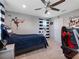 This bedroom has soft carpet, a ceiling fan, a window with blue curtains, and is decorated with sports decor at 676 Bishop Bay Loop, Apopka, FL 32712