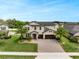 Well-manicured home with palm trees, a paver driveway, and a two-car garage under a blue sky at 676 Bishop Bay Loop, Apopka, FL 32712