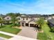Well-manicured home with palm trees, a paver driveway, and a two-car garage under a blue sky at 676 Bishop Bay Loop, Apopka, FL 32712