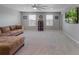 Spacious living room with plush carpeting, comfortable seating, ceiling fan, and a mounted flat screen television at 676 Bishop Bay Loop, Apopka, FL 32712