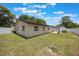 The home has a large, fenced backyard under a blue sky with a concrete patio and lush lawn at 725 Laurel Way, Casselberry, FL 32707