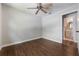 An open doorway leads to a bathroom off this bedroom with wood-look flooring and a ceiling fan at 725 Laurel Way, Casselberry, FL 32707