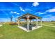Community gazebo featuring picnic tables and seating with playground in background at 914 Poppy Ln, Dundee, FL 33838
