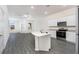 Bright, open kitchen featuring granite countertops, stainless steel appliances, and modern gray wood-look floors at 914 Poppy Ln, Dundee, FL 33838