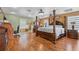 Spacious main bedroom with hardwood floors, a large four-poster bed, dresser and adjoining bathroom at 5208 Oakdale Rd, Haines City, FL 33844