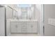 Bright bathroom featuring double sinks, a large mirror, and white cabinets at 12950 Sw 38Th Cir, Ocala, FL 34473