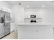 Bright kitchen with stainless steel appliances, white cabinets and a large center island with quartz countertop at 176 River Front Way, Edgewater, FL 32141