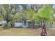 Quaint home featuring a lush lawn, mature trees, and a pop of color from the turquoise shutters at 1825 Baldwin Dr, Orlando, FL 32806