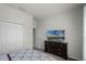 Neutral bedroom showcasing a large dresser with a TV, plush carpet, and closet with bi-fold doors at 256 Whirlaway Dr, Davenport, FL 33837