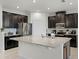 Modern kitchen features sleek, dark cabinetry, stainless steel appliances, and a spacious center island with granite countertop at 256 Whirlaway Dr, Davenport, FL 33837