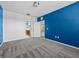 Bedroom with a striking blue accent wall, carpet flooring, and a glimpse of the adjacent bathroom at 8316 Quimby Cir, Davenport, FL 33896