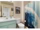 Bright bathroom features a teal vanity, toilet, and a shower with wave-patterned curtain at 8487 Crystal Cove Loop, Kissimmee, FL 34747