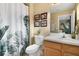 Well-lit bathroom featuring a white vanity, toilet, and a shower with botanical-themed curtain at 8487 Crystal Cove Loop, Kissimmee, FL 34747