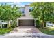 Two-story home featuring a brown garage door, brick driveway, and lush, manicured landscaping at 1052 Avila Ln, Orlando, FL 32803