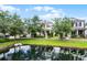 Picturesque view of a two-story home with a pond, mature trees, and lush green lawn at 1052 Avila Ln, Orlando, FL 32803