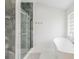 Luxurious bathroom featuring a glass shower with stone tiling and a modern soaking tub near a window at 11400 Lovers Ln, Winter Garden, FL 34787