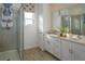 Well-lit bathroom with dual sinks, quartz countertops, a framed mirror, and a glass-enclosed walk-in shower at 1255 Stockwell Ave, St Cloud, FL 34771