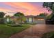 Charming single-story home with brick driveway and lush landscaping, enhanced by a beautiful sunset at 1440 Roosevelt St, Orlando, FL 32804