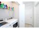 Bright laundry room with white washer and dryer, storage shelf with cleaning supplies, and tile flooring at 146 Loblolly Ln, Davenport, FL 33837