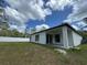 Rear exterior view showing a covered patio, a well-manicured lawn and partial fencing at 1476 11Th Ave, Deland, FL 32724