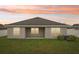 The back of the house is shown with its manicured lawn at sunset at 1846 Galloway Ter, Winter Haven, FL 33881