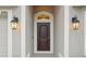 Close up of front door, framed with outdoor lights, elegant trim, and sidelight window with a stylish arch at 1846 Galloway Ter, Winter Haven, FL 33881