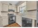 Galley kitchen featuring white cabinets, black appliances, wood flooring, and natural light at 200 Saint Andrews Blvd # 1603, Winter Park, FL 32792
