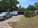 View of the driveway and carport, featuring a truck, trailer, and mature trees around the property at 2464 Lotafun Ave, Winter Park, FL 32789