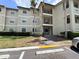 Exterior view of a multi-story building with a landscaped lawn, parking, and community charm at 3028 Parkway Blvd # 105, Kissimmee, FL 34747