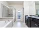 Well-lit bathroom featuring a soaking tub, glass-enclosed shower, and granite-topped vanity at 3413 Lilac, Davenport, FL 33897
