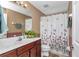 Bathroom with a wooden vanity, shower and tub featuring a flower-patterned shower curtain at 4037 Se 40Th St, Ocala, FL 34480