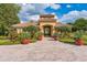 Community clubhouse entrance featuring manicured landscaping, red potted plants, and tile roofing at 442 Anessa Rose Loop, Ocoee, FL 34761