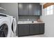 Well-organized laundry room featuring gray cabinets, a utility sink, washer, and dryer at 4709 Flagstaff Ct, Orlando, FL 32820