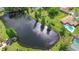 Stunning aerial view of a serene pond surrounded by lush greenery, with homes featuring private pools at 6402 Beechnut Dr, Lakeland, FL 33813