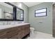 Bathroom features dual sink vanity, framed mirrors, updated lighting, and tiled shower at 6402 Beechnut Dr, Lakeland, FL 33813