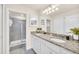 Well-lit bathroom with double vanity, granite countertop, framed mirrors, and walk-in shower at 7487 Oakmoss Loop, Davenport, FL 33837