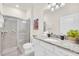 Bright bathroom featuring granite countertop vanity and glass-enclosed tiled shower at 7487 Oakmoss Loop, Davenport, FL 33837