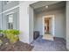 Inviting front entrance featuring a covered porch, gray brick walkway, and well-kept landscaping at 7487 Oakmoss Loop, Davenport, FL 33837