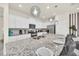 Modern kitchen showcasing granite countertops, stainless appliances, white cabinetry, and pendant lighting over the large island at 7487 Oakmoss Loop, Davenport, FL 33837